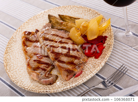 On plate two pieces of barbecue beef with fried vegetables - eggplant slices and green bell peppers On plate two pieces of barbecue beef with fried vegetables - eggplant slices and green bell peppers 106368071