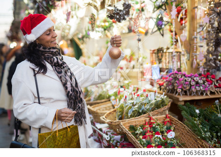 Latin American woman chooses Christmas souvenirs and toys 106368315