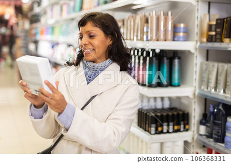 Hispanic woman choosing hair care treatments in cosmetics store 106368331