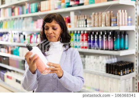 Adult Latina choosing haircare cosmetics in specialized boutique Adult Latina choosing haircare cosmetics in specialized boutique 106368341