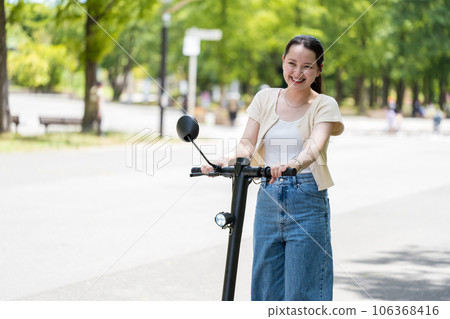 年輕可愛的女人在閃亮的陽光和綠樹下用電動踢腳板清爽地奔跑 | 電動踢腳板圖片 年輕可愛的女人在閃亮的陽光和綠樹下用電動踢腳板清爽地奔跑 | 電動踢腳板圖片 106368416