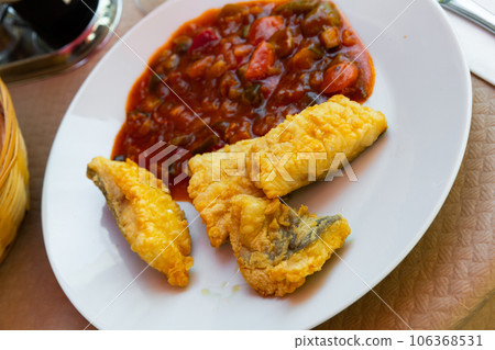 Codfish frying in batter and served with stewed ratatouille 106368531