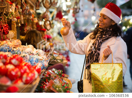 Woman are preparing for Christmas and choosing balls on tree 106368536