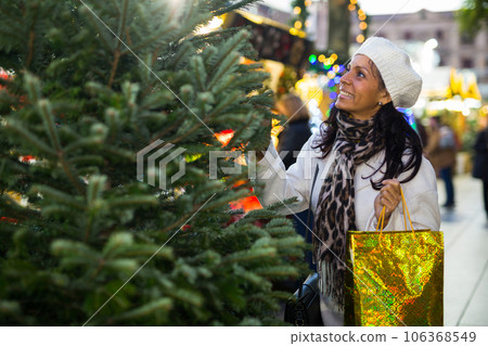 Portrait of a Latin American woman choosing a Christmas tree Portrait of a Latin American woman choosing a Christmas tree 106368549