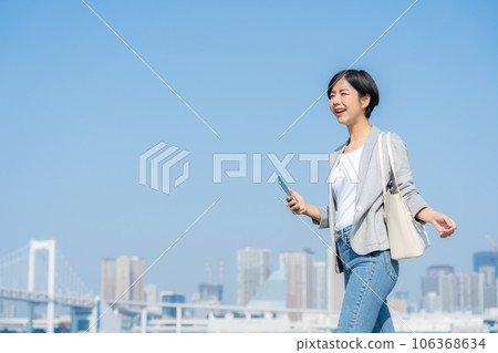 Young office casual business woman operating a smartphone in an office district Young office casual business woman operating a smartphone in an office district 106368634