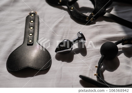 Black leather bdsm set on white sheet. Black leather bdsm set on white sheet. 106368942