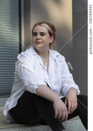 Beautiful Smiling Stylish Plus Size 20s Woman, Zoomer Sit On Concrete Street Stairs Outdoors On Summer Day, Looking Away. Young Caucasian Student Have Fun . Urban Lifestyle. Vertical Plane 106369485