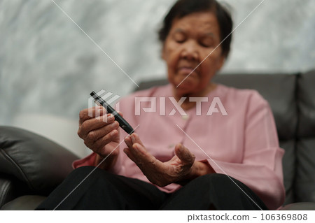 close up senior woman using glucometer checking blood sugar level at home. diabetes concept. close up senior woman using glucometer checking blood sugar level at home. diabetes concept. 106369808