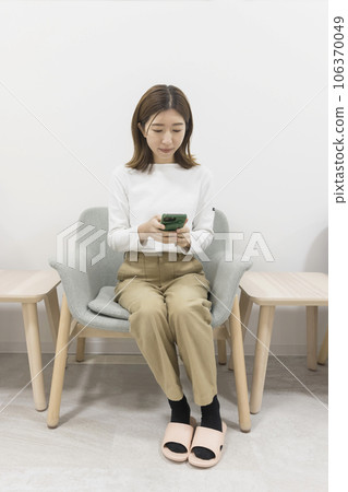 Young woman looking at smartphone in hospital waiting room 106370049