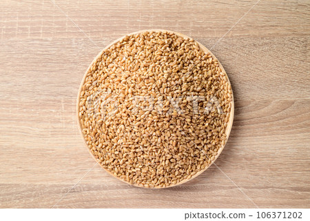 Whole wheat grain on plate with wooden background, Food ingredients, Table top view 106371202