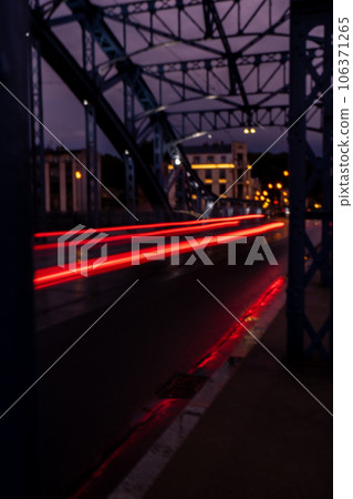 Defocused Lights of cars at night in Krakow bridge. Street line lights. Night highway city. Long exposure photograph night road. Colored bands of red light trails on the road. Background wallpaper  106371265
