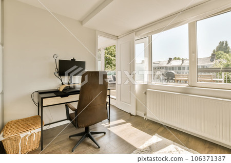 a home office with a desk and chair in front of a large window looking out onto the street below it 106371387