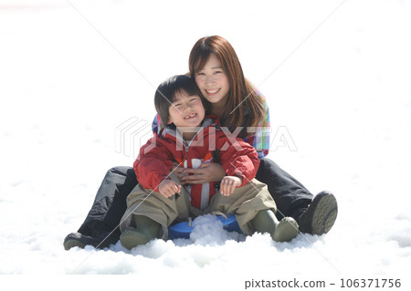 Parent and child playing on a sled 106371756