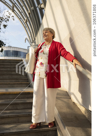 Elderly Mature Lady In Casual Clothes Moving Downstairs In Underground Crossing. Smiling Beautiful Real Female With Gray Hair Holds Railing. Retirement. Vertical Plane 106371808