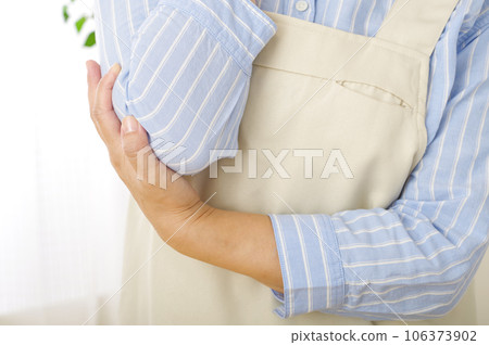 A woman in an apron with a painful elbow 106373902
