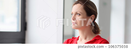 A thoughtful woman in red clothes looks out window A thoughtful woman in red clothes looks out window 106375038
