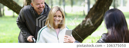 A smiling woman is a disabled person in a park with a friend A smiling woman is a disabled person in a park with a friend 106375050