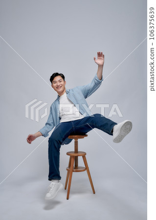 Photo portrait young man smiling sitting on wooden chair isolated on white background 106375639