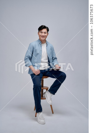 Image of young Asian man sitting on chair Image of young Asian man sitting on chair 106375673