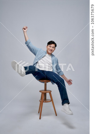 Cheerful joyful man sitting chair hand fist up rejoice empty space isolated on white background Cheerful joyful man sitting chair hand fist up rejoice empty space isolated on white background 106375679