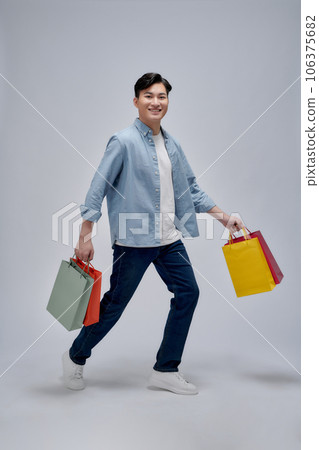 A portrait of happy young asian man holding shopping bags, full body 106375682