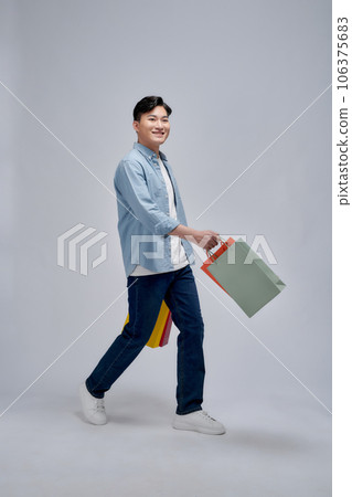 Young positive man hold bags from shopping store advert satisfied 106375683