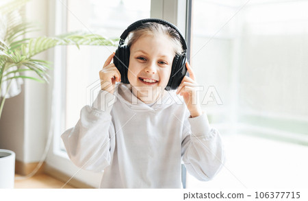 Cute little girl listening to music in headphones 106377715