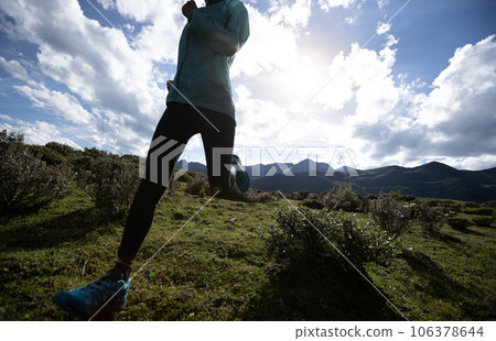 Woman trail runner cross country running at high altitude mountain peak 106378644