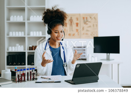 Attractive African female doctor talking while explaining medical treatment to patient through a video call with laptop in office or laboratory Attractive African female doctor talking while explaining medical treatment to patient through a video call with laptop in office or laboratory 106378849