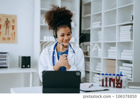Attractive African female doctor talking while explaining medical treatment to patient through a video call with laptop in office or laboratory Attractive African female doctor talking while explaining medical treatment to patient through a video call with laptop in office or laboratory 106378850