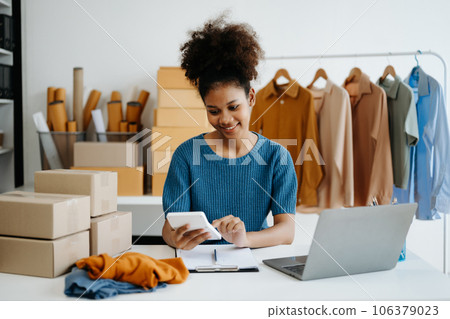 Young African woman running online store Startup small business SME, using smartphone or tablet taking receive and checking online purchase shopping order in office Young African woman running online store Startup small business SME, using smartphone or tablet taking receive and checking online purchase shopping order in office 106379023