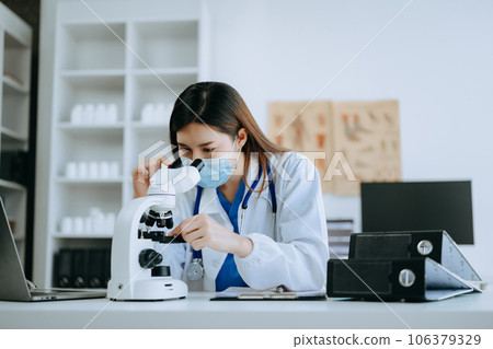 Young scientists conducting research investigations in a medical laboratory, a researcher in foreground is using a microscope in laboratory for medicine.  . 106379329