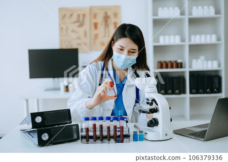 Young scientists conducting research investigations in a medical laboratory, a researcher in foreground is using a microscope in laboratory for medicine.  . 106379336