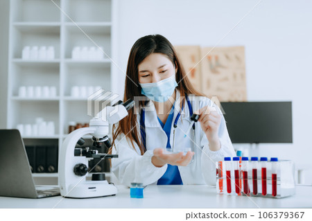 Young scientists conducting research investigations in a medical laboratory, a researcher in foreground is using a microscope in laboratory for medicine. . Young scientists conducting research investigations in a medical laboratory, a researcher in foreground is using a microscope in laboratory for medicine. . 106379367