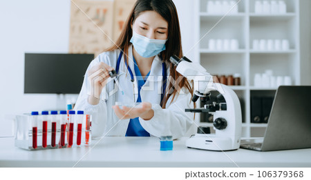 Young scientists conducting research investigations in a medical laboratory, a researcher in foreground is using a microscope in laboratory for medicine.  . 106379368