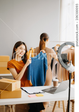 Fashion blogger concept, Young Asian women selling clothes on video streaming.Startup small business SME, using smartphone or tablet taking receive and checking. 106380093