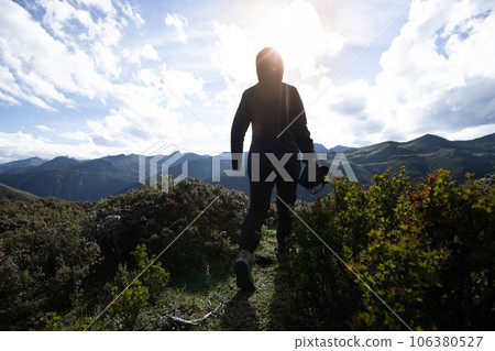 Woman photographer walking in summer high altitude mountains, China Woman photographer walking in summer high altitude mountains, China 106380527