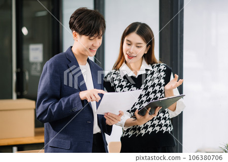 Asian business colleague business presents and explains and using laptop and tablet. Teamwork, financial marketing team, while sitting in modern office room.. 106380706