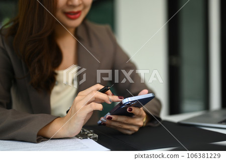 Cropped shot of woman holding smartphone using mobile app, checking social media, texting message 106381229