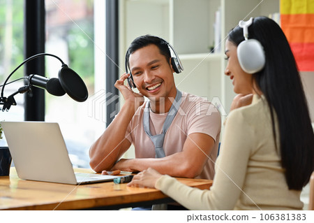 Positive gay male radio host discussing various topics with guest while streaming live audio podcast in studio Positive gay male radio host discussing various topics with guest while streaming live audio podcast in studio 106381383