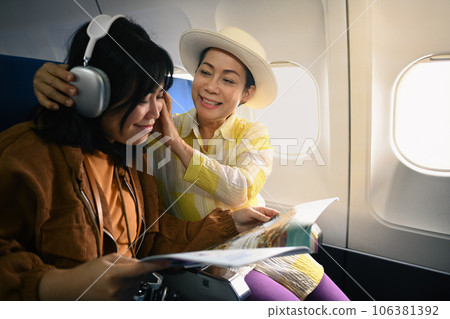 Positive senior woman and daughter listening to music during fly in airplane. Holidays and transportation concept 106381392