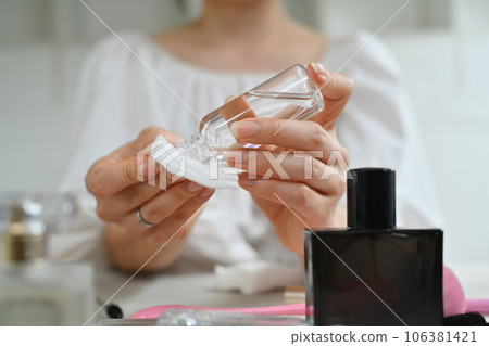 Cropped shot of young woman pouring micellar water from bottle on cotton pad while making daily beauty routine at home Cropped shot of young woman pouring micellar water from bottle on cotton pad while making daily beauty routine at home 106381421