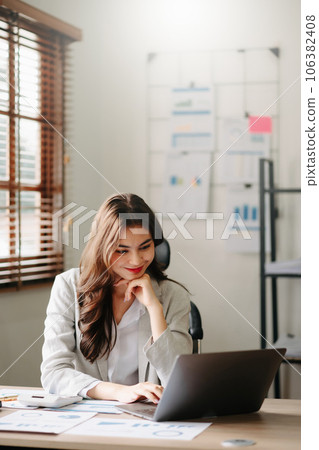 Young beautiful woman typing on tablet and laptop while sitting at the working wooden table office Young beautiful woman typing on tablet and laptop while sitting at the working wooden table office 106382408