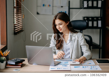 Confident Asian woman with a smile standing holding notepad and tablet at the office.. 106382409