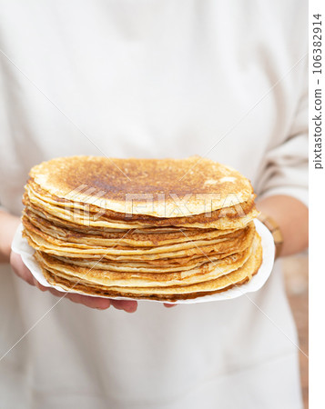 Women holding white plate with pile thin pancakes Women holding white plate with pile thin pancakes 106382914