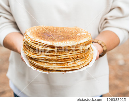Women holding white plate with pile thin pancakes Women holding white plate with pile thin pancakes 106382915