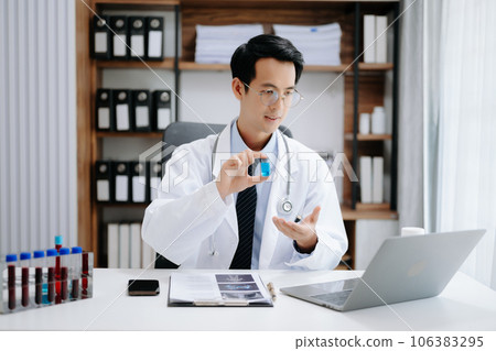Attractive female doctor talking while explaining medical treatment to patient through a video call with laptop in modern office 106383295