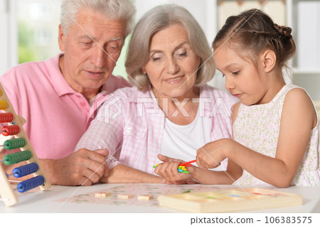 Portrait of happy grandparents with granddaughter using abacus together Portrait of happy grandparents with granddaughter using abacus together 106383575