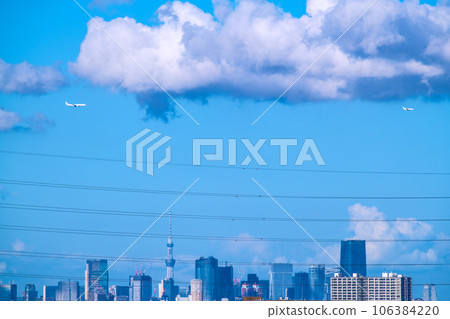 Tokyo cityscape, Japan. Two aircraft. Aircraft line up and pass over the city center. Post-corona virus recovery, aviation demand recovery = August 106384220