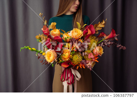 Woman holding orange Autumn Colorful fall bouquet. blooming flowers festive background, autumn orange and red flowers. bouquet floral card. Mothers day, International Women's Day. Woman holding orange Autumn Colorful fall bouquet. blooming flowers festive background, autumn orange and red flowers. bouquet floral card. Mothers day, International Women's Day. 106387797